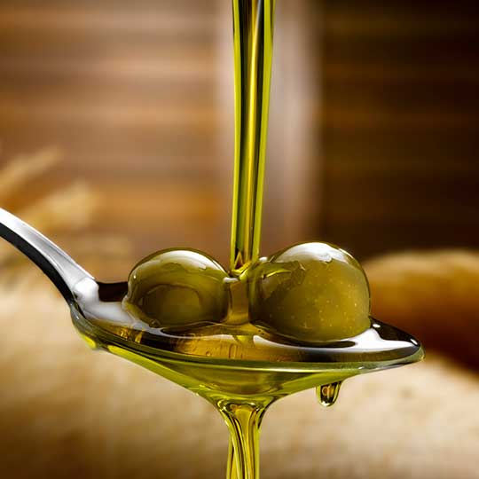 aceite de oliva virgen extra sobre una cuchara con aceitunas