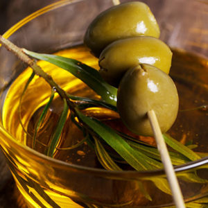 Baso con aceite de oliva virgen extra y tres aceitunas por encima