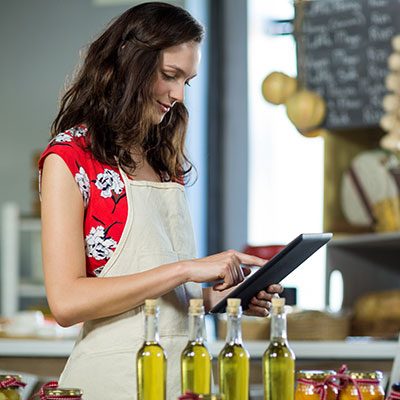 Mujer en la cocina con una tablet en la mano pensando en comprar aceite de oliva online